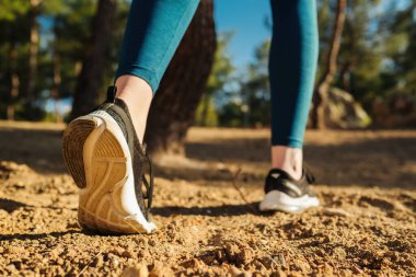 Mavi yoga pantolonu ve siyah spor ayakkabısı giyen genç bir kadın başlamaya hazırlanıyor. Yürüyüş, açık hava sporları, yeni gün, spor ve sağlıklı yaşam konsepti.
