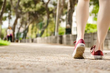 Şehir parkında spor kıyafetler giyen genç ve güzel bir kadın. Açık hava koşucusu başlangıç için hazırlanıyor. Yürüyüş, açık hava sporları, yeni gün, spor ve sağlıklı yaşam konsepti.