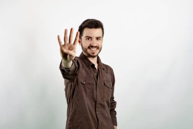 Beyaz arka planda izole edilmiş tişört giyen mutlu genç adam gülümseyerek dört numarayı gösteriyor ve işaret ediyor..