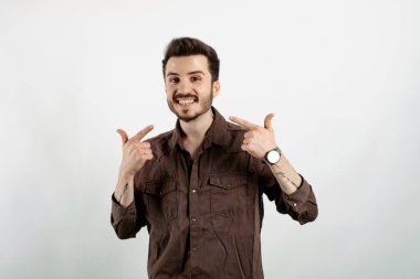 Beyaz arka planda yalnız poz veren beyaz tişörtlü genç bir adam. Diş sağlığı konsepti.