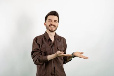 Mutlu, sıradan giyinen, beyaz arka planda soyutlanmış poz veren, yüzünde kocaman bir gülümseme olan bir adam..