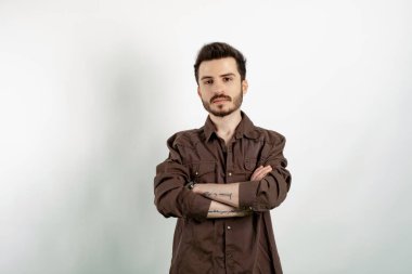 Beyaz arka planda izole edilmiş günlük kıyafetler giyen yakışıklı beyaz adam kameraya bakarak kollarını kavuşturdu. Pozitif kişi.