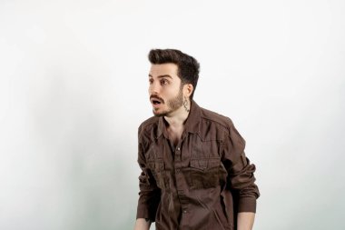 Yakışıklı, sıradan kıyafetler giyen, beyaz arka planda yalnız poz veren, koca gözlü ve ağzı açık bir genç. Haberler karşısında şok olmuş, boş fotokopi alanı..