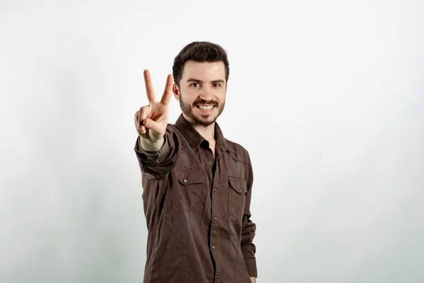 Happy young man wearing shirt posing isolated over white background showing and pointing up with fingers number two while smiling.