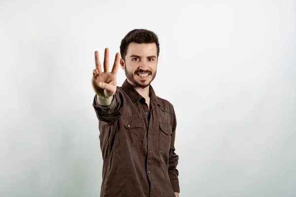 Happy young man wearing shirt posing isolated over white background showing and pointing up with fingers number three while smiling.