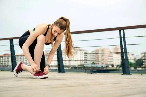Şehir parkında spor kıyafetler giyen esmer bir kadın. Dantelli koşu ayakkabıları bağlıyor. Koşmaya hazırlanıyor. Koşan kız egzersiz motivasyonu sağlık ve zindelik.