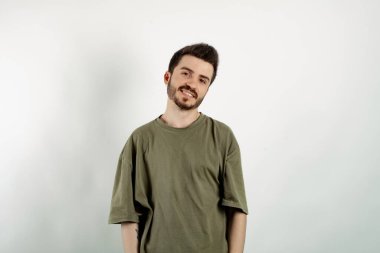 Haki tişört giyen mutlu genç bir adam beyaz arka planda izole edilmiş poz veriyor gülümsüyor ve kameraya bakıyor. Pozitif kişi.