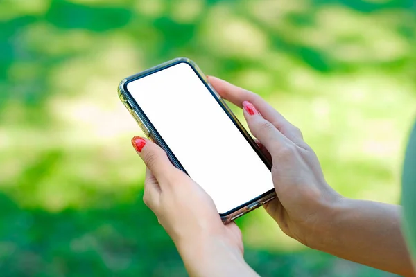 Young beautiful woman wearing turquoise tee on city park, outdoors hands holding mock up smart phone. Close up view.