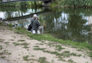 Yaşlı bir adam gölde balık tutuyor.