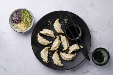 Soya soslu, mikroyeşillikli, susamlı ve siyah pirzola çubuklu tavuk etiyle doldurulmuş Japon hamur köfteleri.