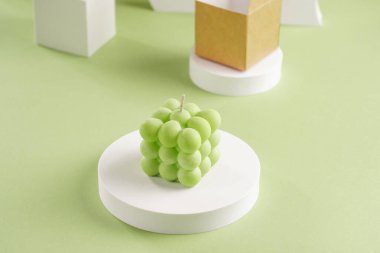 Pastel yeşil yüzey üzerinde mavi, yeşil ve beyaz baloncuk mumlar ve bir ambalaj kutusu