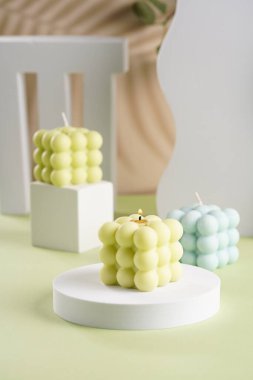 Pastel yeşil bir yüzey üzerinde üç mavi, yeşil ve beyaz baloncuk mumları.