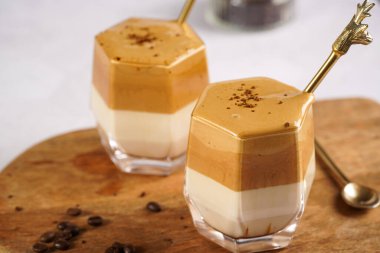 İki bardak modaya uygun Kore içeceği dalgona kahve latte - çırpılmış kahve, şeker ve sıcak su ve beyaz yüzey üzerinde süt katmanları