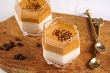 İki bardak modaya uygun Kore içeceği dalgona kahve latte - çırpılmış kahve, şeker ve sıcak su ve beyaz yüzey üzerinde süt katmanları