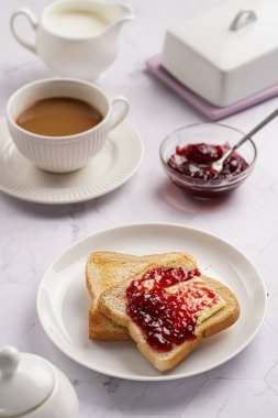 tatlı kahvaltı - tereyağlı tost ekmeği ve beyaz tabakta vişne reçeli, bir fincan kapuçino