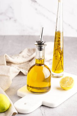 Beyaz mermer arka planda iki şişe zeytinyağı ve taze otlar - kekik -