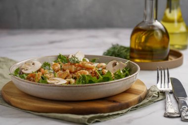 Karides ve şampiyon Arugula salatası, beyaz bir yüzeyde ahşap bir tahtada zeytin yağı ve dereotu.