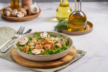 Karides ve şampiyon Arugula salatası, beyaz bir yüzeyde ahşap bir tahtada zeytin yağı ve dereotu.