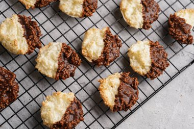 Çikolataya batırılmış birkaç hindistan cevizi taneli kurabiye gri beton yüzey üzerinde fırın rafında, üst görünümde.