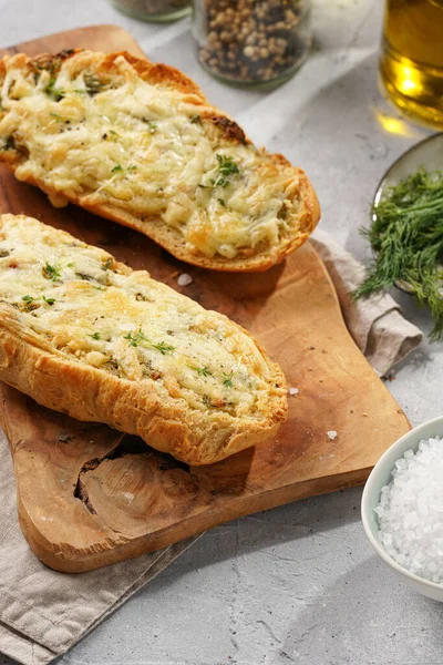 İki parça sarımsaklı ve tereyağlı ekmek - tahtanın üzerinde baget, deniz tuzu, biber, dereotu ve sarımsak karanfili gri beton arka planda, üst manzara