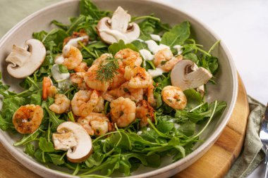 Karides ve şampiyon Arugula salatası, beyaz bir yüzeyde ahşap bir tahtada zeytin yağı ve dereotu.