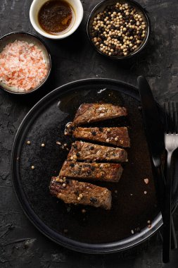 Siyah tabakta pişmiş biftek dilimlenmiş beyaz ve siyah akranlar, kaba deniz tuzu.