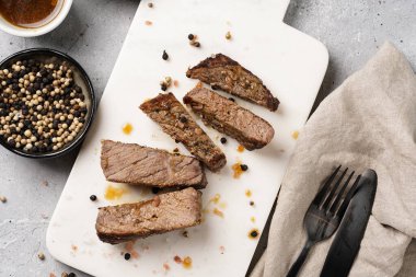 Beyaz mermer tahtada pişmiş biftek dilimlenmiş beyaz ve siyah akranlar, kaba deniz tuzu.