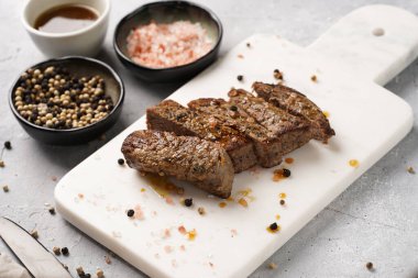 Beyaz mermer tahtada pişmiş biftek dilimlenmiş beyaz ve siyah akranlar, kaba deniz tuzu.