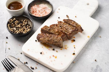 Beyaz mermer tahtada pişmiş biftek dilimlenmiş beyaz ve siyah akranlar, kaba deniz tuzu.