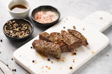 Beyaz mermer tahtada pişmiş biftek dilimlenmiş beyaz ve siyah akranlar, kaba deniz tuzu.