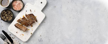 Beyaz mermer tahtada pişmiş biftek dilimlenmiş beyaz ve siyah akranlar, kaba deniz tuzu. Üst görünüm, negatif boşluk, pankart