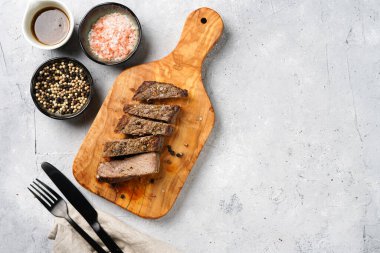 Tahtada pişmiş biftek dilimlenmiş beyaz ve siyah akranlar, kaba deniz tuzu. Üst görünüm, negatif boşluk
