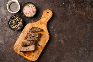 Tahtada pişmiş biftek dilimlenmiş beyaz ve siyah akranlar, kaba deniz tuzu. Üst görünüm, negatif boşluk