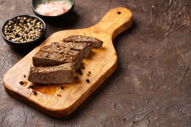 Tahtada pişmiş biftek dilimlenmiş beyaz ve siyah akranlar, kaba deniz tuzu.