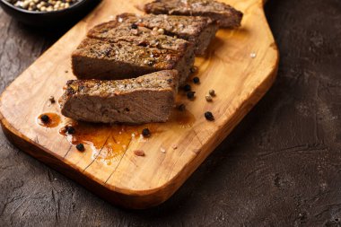 Tahtada pişmiş biftek dilimlenmiş.