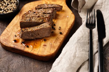 Tahtada pişmiş biftek dilimlenmiş.