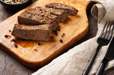 Tahtada pişmiş biftek dilimlenmiş.