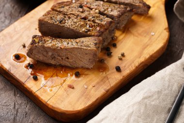 Tahtada pişmiş biftek dilimlenmiş.