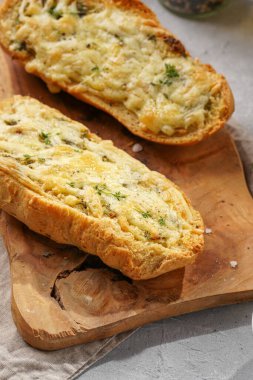 İki parça sarımsaklı ve tereyağlı ekmek - tahtanın üzerinde baget, deniz tuzu, biber, dereotu ve sarımsak karanfili gri beton arka planda, üst manzara