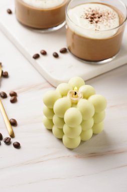 Kahve çekirdekleri ve tatlı tatlı farenin arasında mermer mutfak masasında soluk yeşil bir baloncuk mumu.