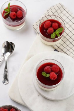 İtalyan sütlü panna cotta ahududu reçeli ve mermer tahtada taze ahududu.