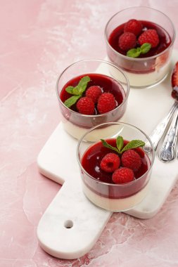 İtalyan sütlü tatlı panna cotta ahududu reçeli, taze ahududu ve pembe yüzeydeki mermer tahtada nane şekeri, kopyalama alanı