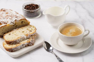 Beyaz çay tabağında kahve kapuçino ve mermer bir masada çalınmış noel pastası.