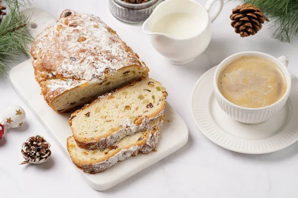 Beyaz çay tabağında kahve kapuçino ve mermer bir masada çalınmış noel pastası.