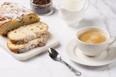 Beyaz çay tabağında kahve kapuçino ve mermer bir masada çalınmış noel pastası.