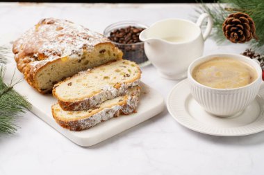 Beyaz çay tabağında kahve kapuçino ve mermer bir masada çalınmış noel pastası.