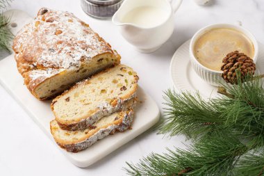 Beyaz çay tabağında kahve kapuçino ve mermer bir masada çalınmış noel pastası.