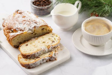 Beyaz çay tabağında kahve kapuçino ve mermer bir masada çalınmış noel pastası.