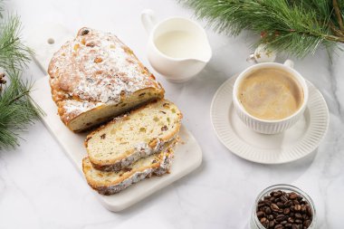 Beyaz çay tabağında kahve kapuçino ve mermer bir masada çalınmış noel pastası.