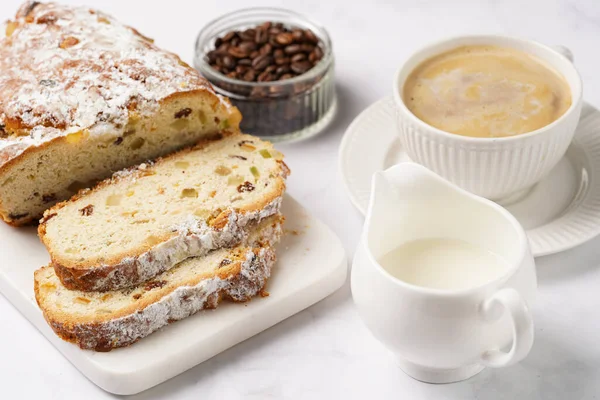 Beyaz çay tabağında kahve kapuçino ve mermer bir masada çalınmış noel pastası.